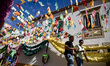 People walk in the streets decorated with paper flower and other decorations for during th...
