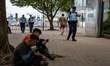 Police officers walks pass workers siting under a tree on October 25, 2023 in Hong Kong, C...