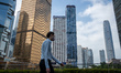 A man walks pass office buildings on October 25, 2023 in Hong Kong, China. John Lee today...