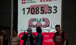 People walk pass an electronic display board for the Hang Seng Index on October 25, 2023 i...