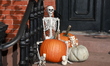 Halloween decorations of pumpkins and skeletons cover the doorway and staircase of a Green...
