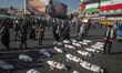 People stand next to the shroud-wrapped packages, symbolizing the bodies of Palestinian ch...