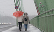 A couple is crossing the Severins Bridge in Cologne, Germany, on December 4, 2023, as snow...