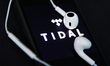 Headphones and Tidal logo displayed on a phone screen are seen in this illustration photo...