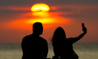 A couple is taking a selfie at sunset in Colombo, Sri Lanka, on December 26, 2023. 