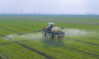 Workers are driving a plant protection machine to spray pesticide and foliar fertilizer on...