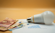 A chart showing electricity prices is displayed alongside a LED lamp and banknotes. 