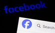 Facebook logo displayed on a phone screen and Facebook website displayed on a laptop scree...