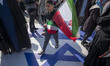 A young Iranian boy is carrying an Iranian flag while walking on an Israeli flag on Azadi...