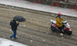 A woman is riding a scooter on a snowy street during heavy snowfall in Srinagar, Indian Ad...
