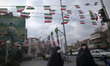 Two young veiled Iranian women are walking under Iranian flags in southern Tehran, amid th...