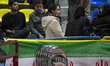 A young woman, not wearing a mandatory headscarf, is standing behind an Iranian flag while...