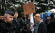 A protester is standing in front of riot police with a placard that reads 'M the Prefet, o...