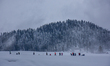 People are walking on a snow-covered meadow during a blizzard at the ski resort in Gulmarg...