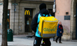 A Glovo delivery person is standing in front of McDonald's on a city street in Krakow, Pol...