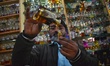 A shopkeeper is filling a glass bottle with non-alcoholic perfume known as 'Attar' at his...