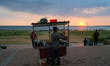A street food vendor is selling food from his cart at sunset on the Galle Face promenade i...