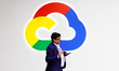 A South-Asian man is walking past the Google Cloud logo at their pavilion during the Mobil...