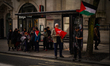 People are marching in central London, holding banners and Palestinian flags in support of...