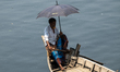 Boatmen are taking shelter under umbrellas as they wait for passengers during a heatwave o...