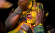 Indian women play with colored powder,on the eve of Holi Festival, in Allahabad on March 2...