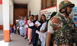 People are standing in queues and showing their voting cards at a polling station during t...