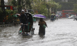 A woman is walking through a waterlogged road during rainfall following the landfall of Cy...