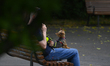 A small dog is seen on a man's lap in a park in Warsaw, Poland on 23 May, 2024. 