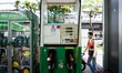 A motorcycle taxi driver is fueling up their vehicle at a gas pump in the morning in Bangk...