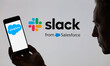 The Salesforce logo is being displayed on a smartphone, with the Slack logo in the backgro...