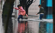 Women are walking with their legs submerged in the water, trying to cross Vicente Villada...