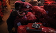 A vendor is looking at his mobile phone as he is waiting for a customer in an onion shop a...