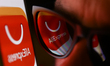 AliExpress logo displayed on a phone screen and reflected on sunglasses is seen in this il...