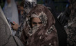 A young veiled Iranian woman is standing in line at a polling station in a holy shrine dur...