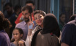 A young Iranian woman is flashing a Victory sign while standing in line at a mosque that i...