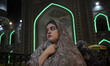 A young veiled Iranian woman is standing at a polling station in a holy shrine during Iran...