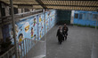Two Iranian women are arriving at a school that is being used as a polling station to cast...