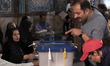 An Iranian man is pointing at a ballot box while attending a mosque that is being used as...
