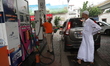 A worker is filling a car with petrol as he gestures towards the fuel barometer for the pa...