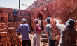 Brick factory workers transporting ready-to brick red brick truck-mounted outside the plan...