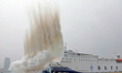 A national defense mobilization support team is camouflaging the ship's hull with smoke sc...