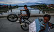 A boy is performing stunts on his bicycle on a bridge over River Jhelum in Sopore, Jammu a...