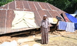 People stand in their broken house by flood water in Feni District, Bangladesh, on August...