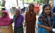 Flood water affects people carrying relief bags in Feni District, Bangladesh, on August 30...