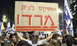An Israeli protester carries a placard reading ''stop obeying, revolt'' as dozens of thous...