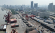 A crane loads corn from a cargo ship docked on the Yangtze River terminal into a container...