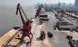 A crane loads corn from a cargo ship docked on the Yangtze River terminal into a container...