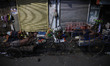 Labourers take a nap along a roadside at a wholesale market during the early morning in Ko...
