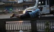 A laborer rests on a railing of a bridge along the roadside at a wholesale market during t...