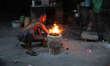 A roadside food vendor lights a coal oven before he starts his business in Kolkata, India,...